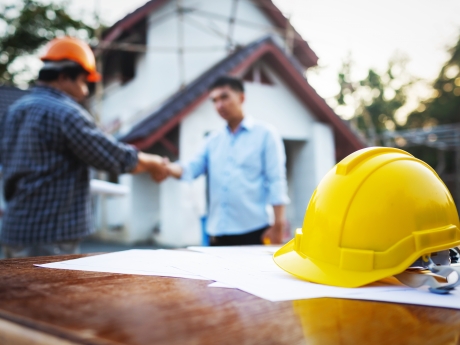 Contractor and man shaking hands in front of house
